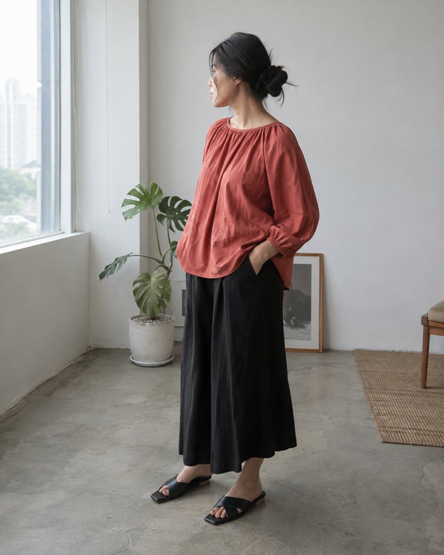 Model mengenakan Blouse Lana coral dan Kulot Tera hitam di studio Rupa Label